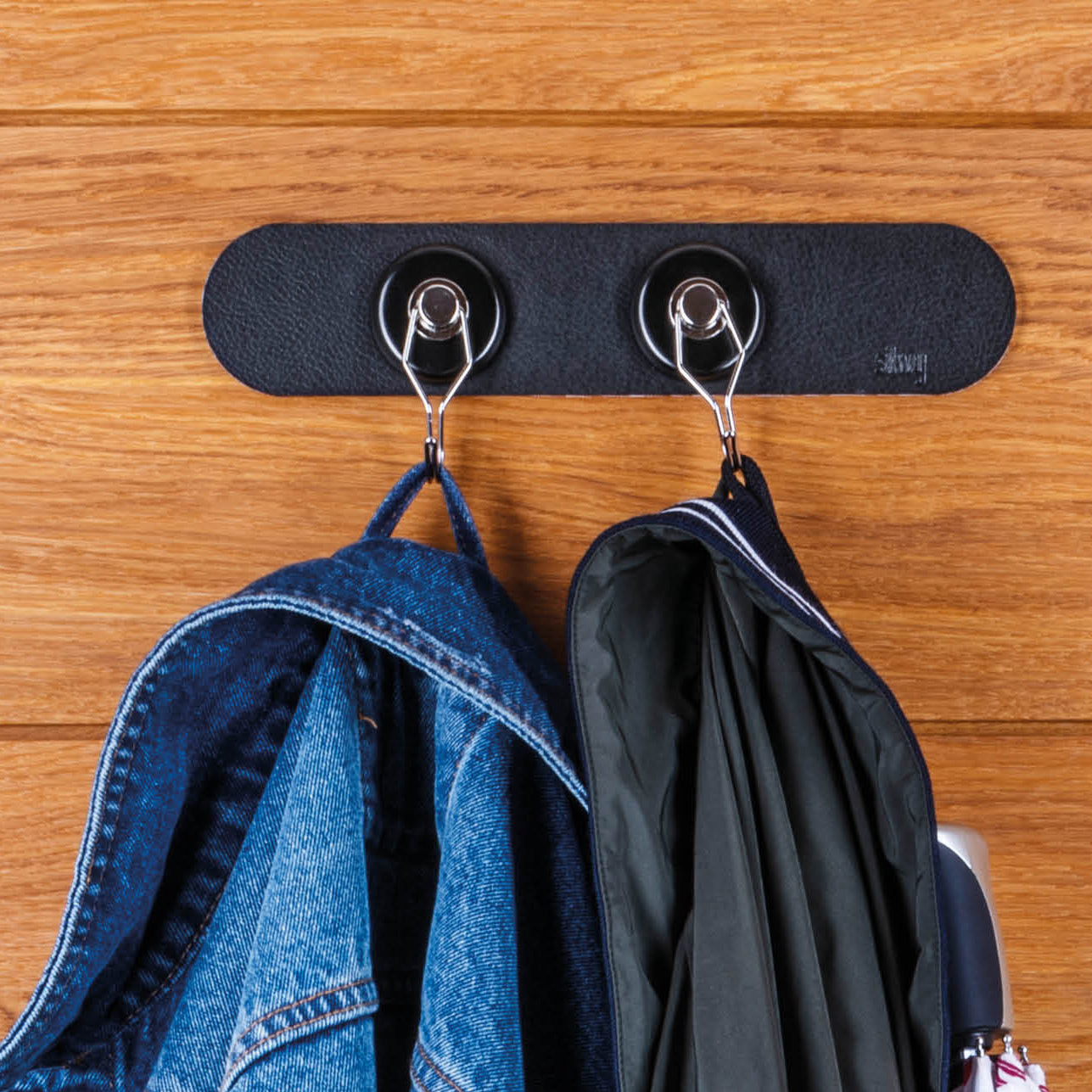 Magnet-Haken mit schwarzer Metall-Leiste und daran hängenden Jacken