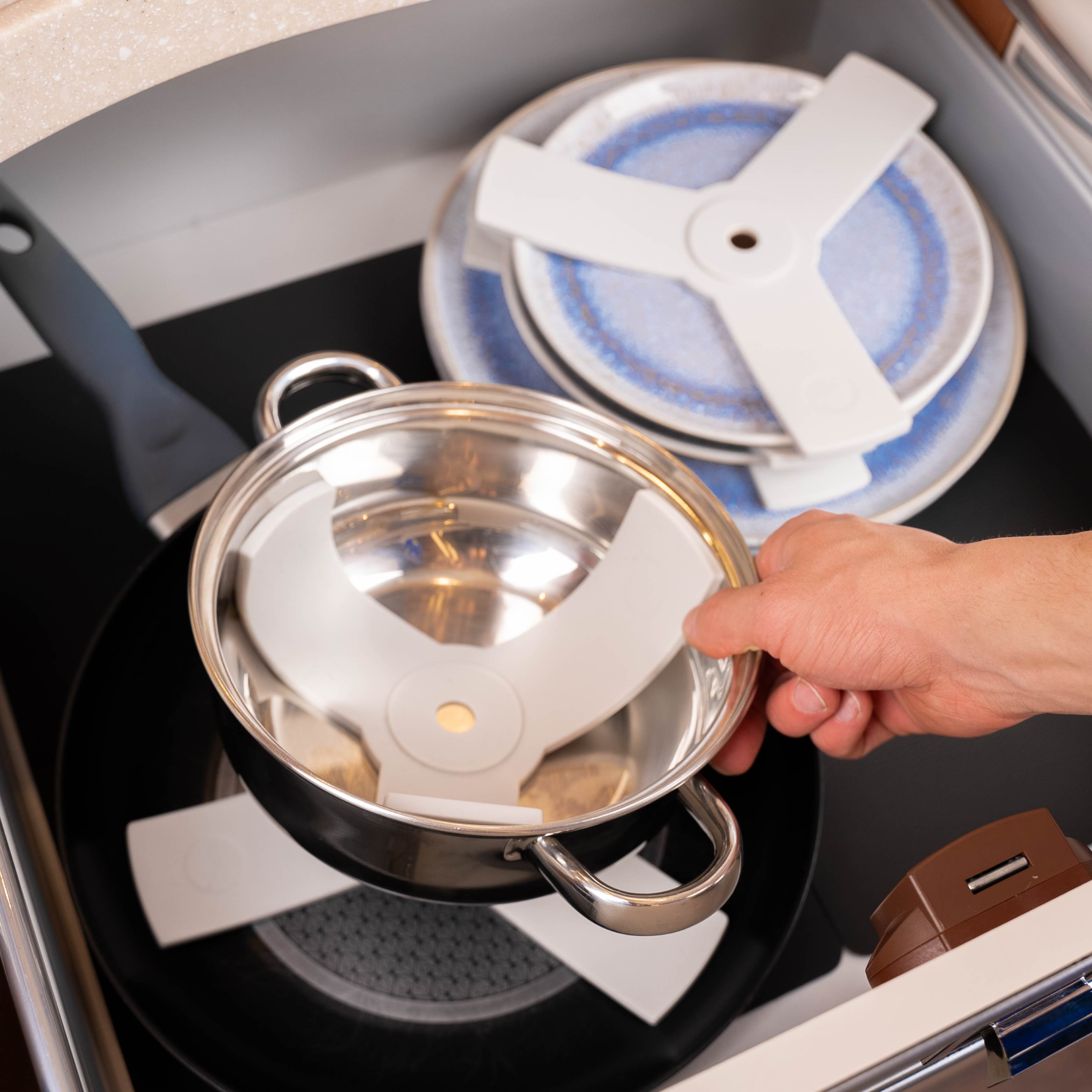 Magnet-Teller mit Sandwiches aufeinander gestapelt sowie Pfanne und Topf aufeinander gestapelt mittels Sandwich auf Metall-Matte