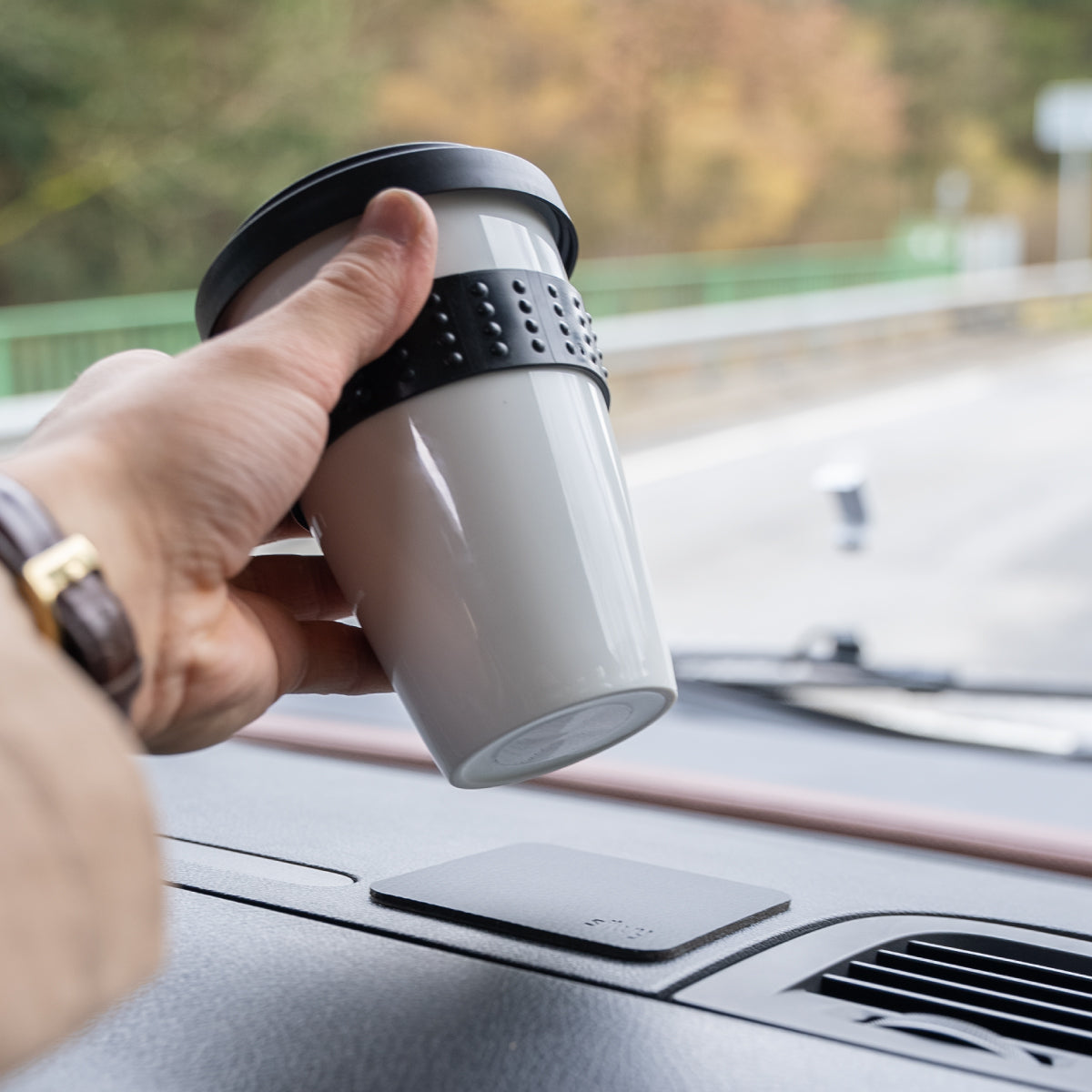 Porzellan-Cup mit Magnet wird auf Pad abgestellt auf Armaturenbrett