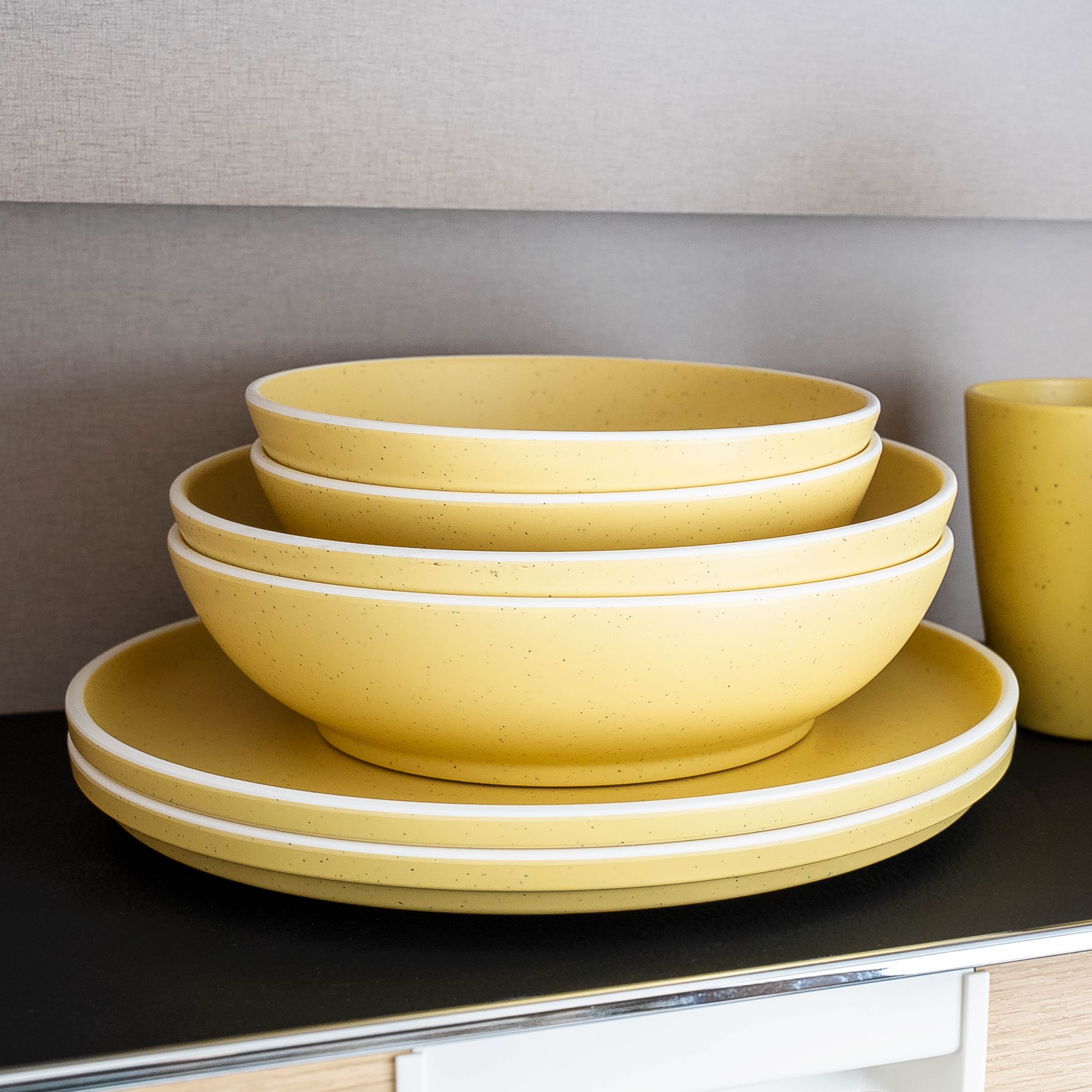 Brunner Geschirr YELLOW gestapelt auf Metall-Matte im Schrank