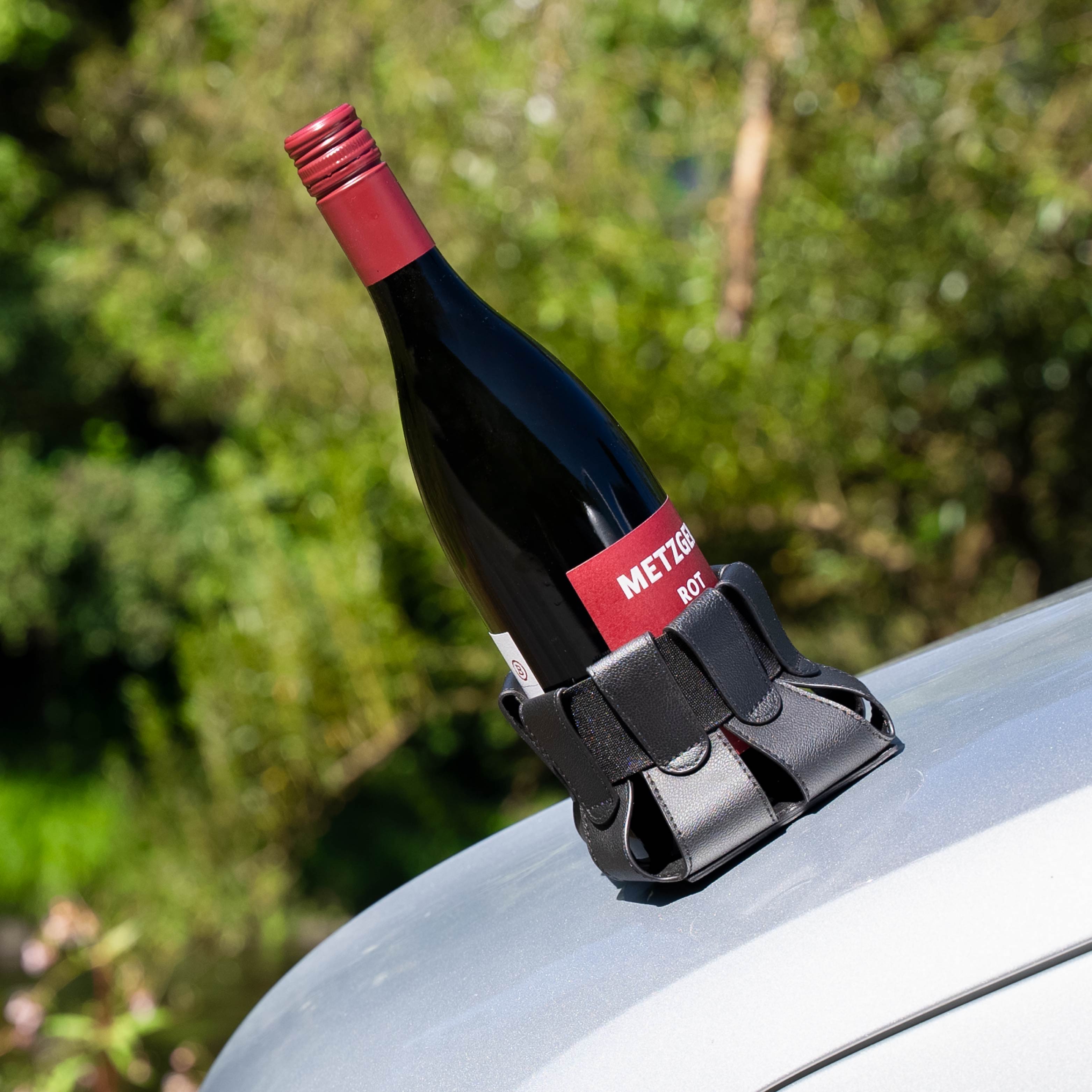 Magnet-Flaschenhalter mit Flasche Rotwein auf metallischer Oberfläche 