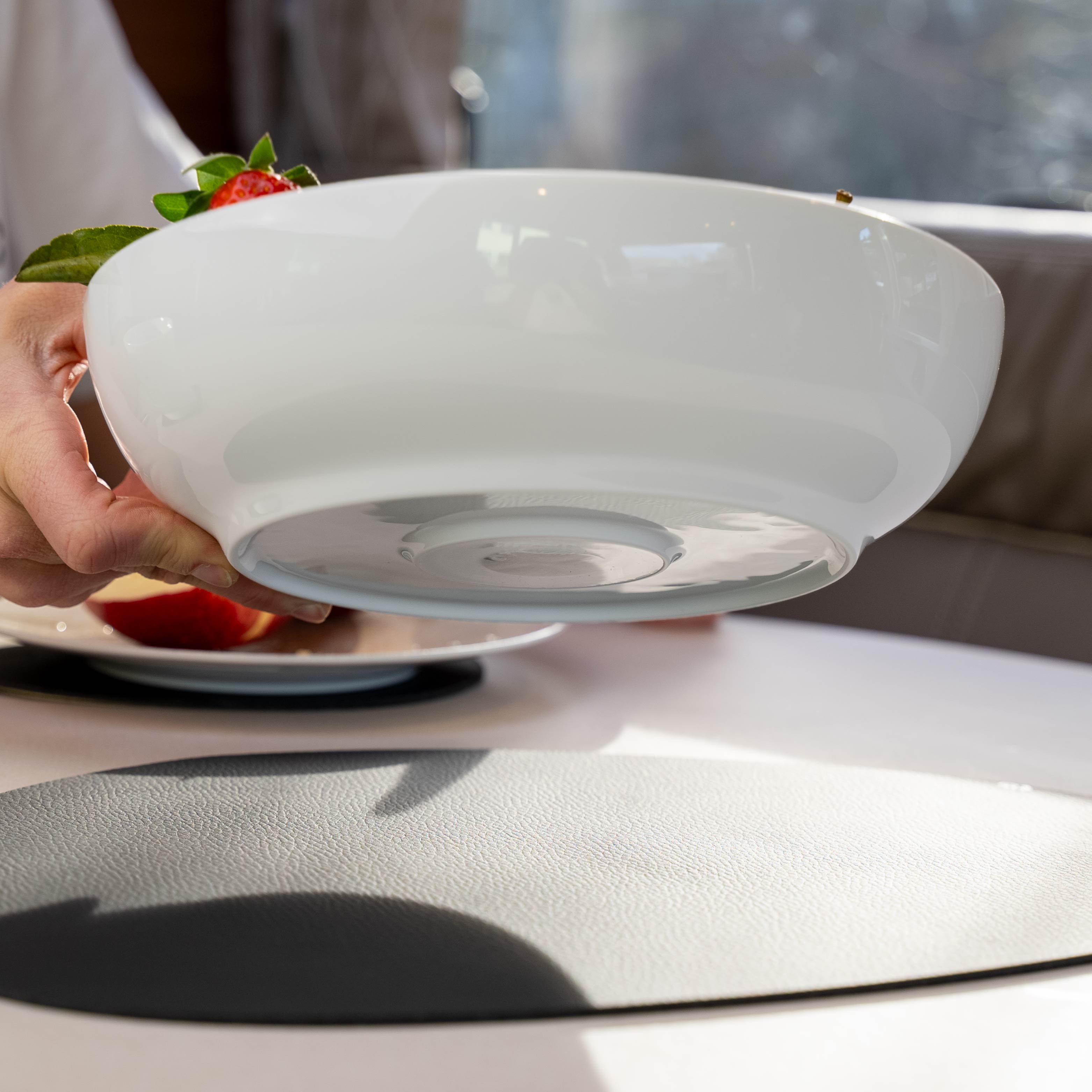 Magnet-Porzellan-Food-Bowl Classic mit integriertem Magneten im Boden in der Luft gehalten und Metall-Matte in schwarz auf Tisch 
