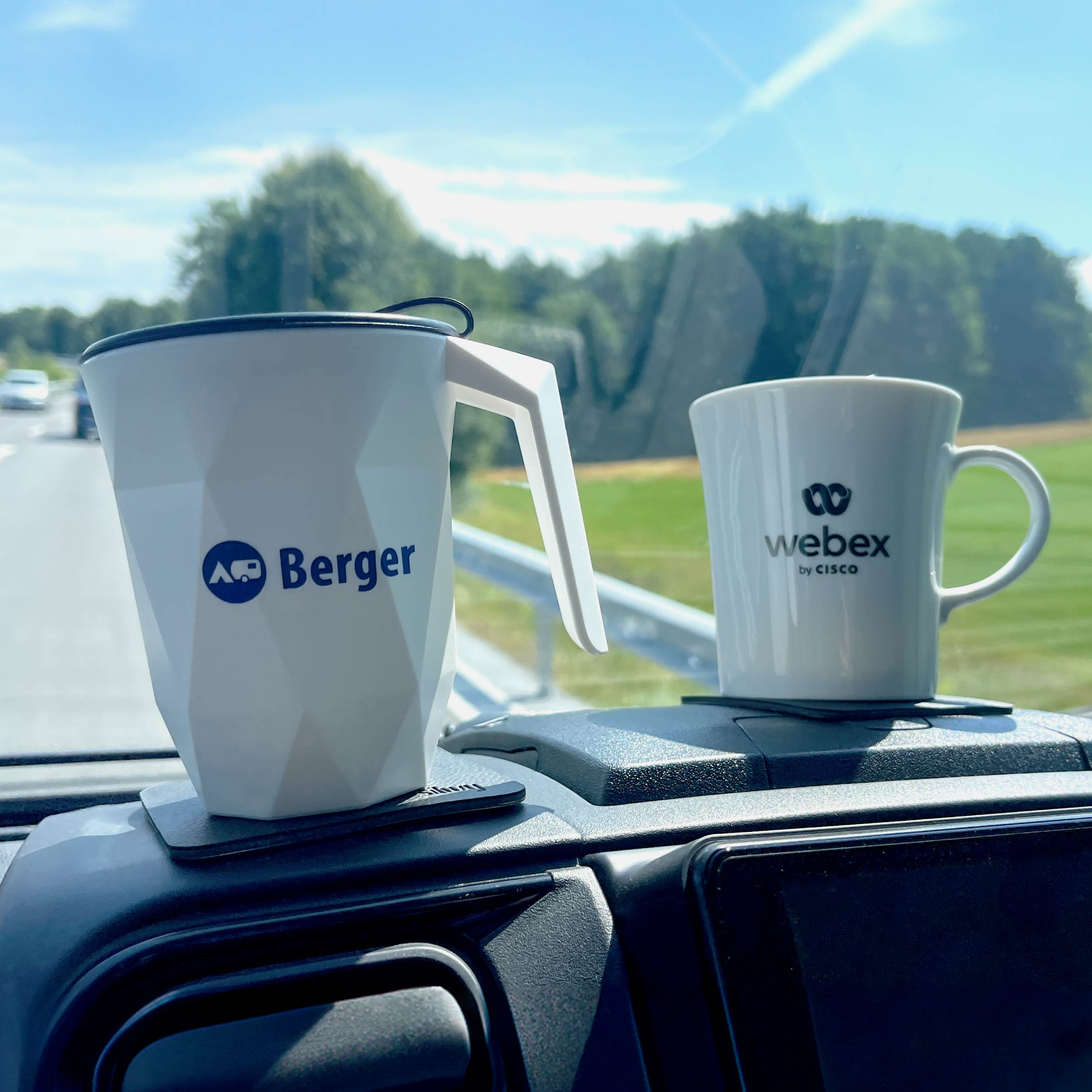 Kunststoff- und Porzellantasse auf Pad im Auto vorne auf Armaturenbrett mit Kundenlogos