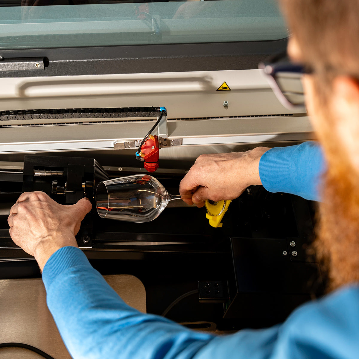 Mitarbeiter Ludwig graviert ein Weinglas 