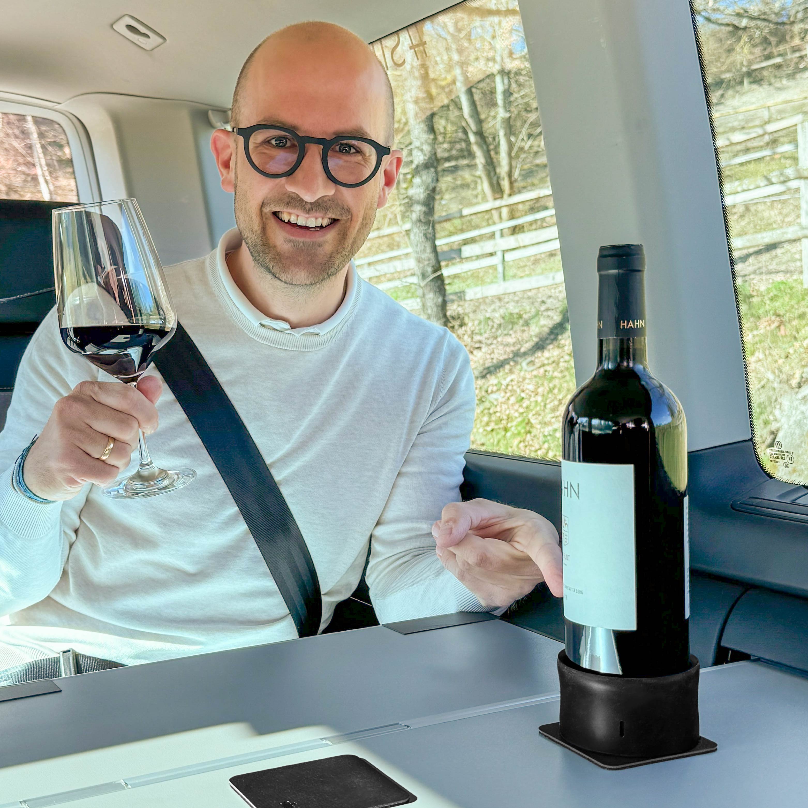 Magnet-Halter mit Weinflasche, Person auf dem Rücksitz hält Glas in der Hand