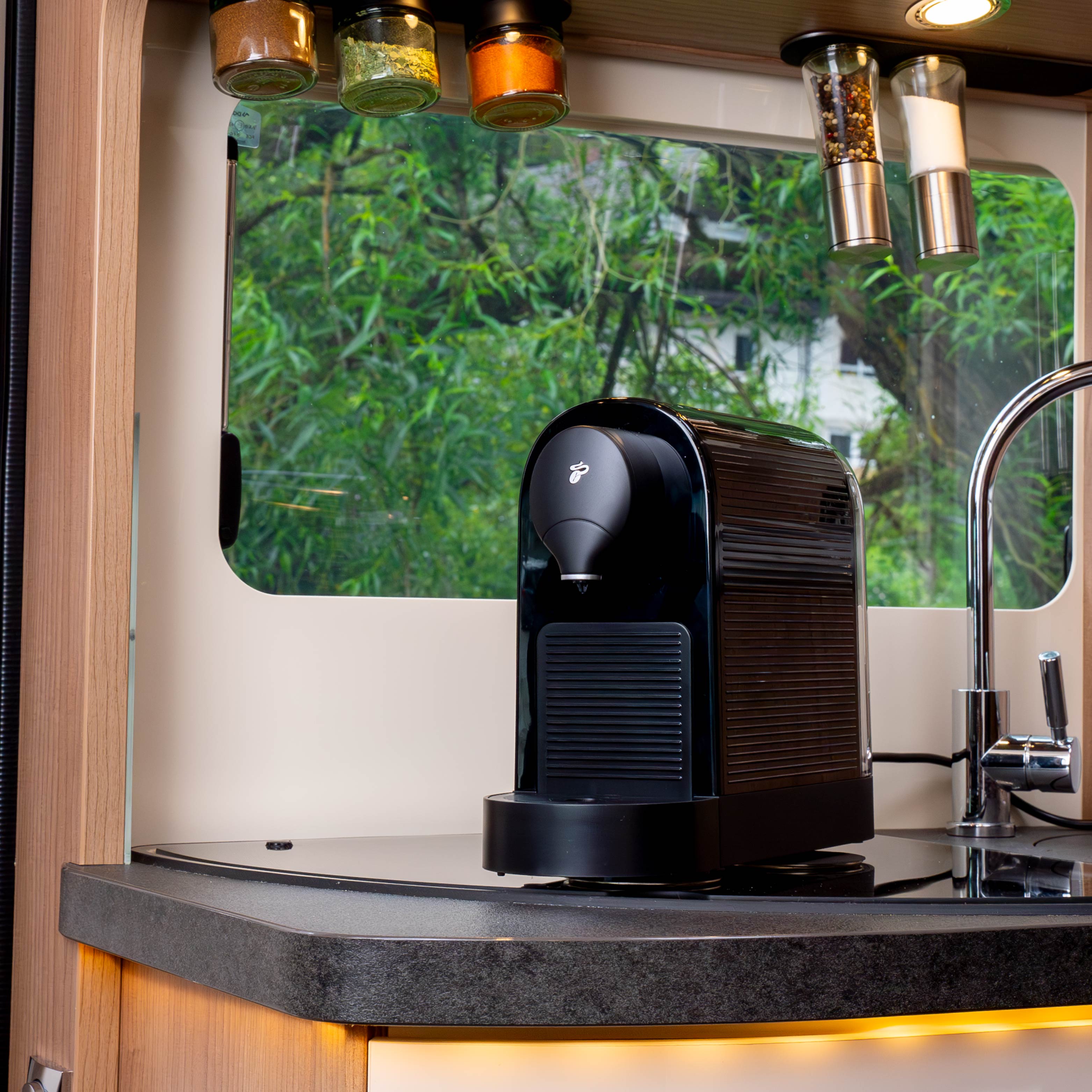 Power Bundle XXL - schwarze Kaffeemaschine befestigt mit Power-Magneten an Metall-Nano-Gel-Pads in Camper. An Decke sind Magnet-Gewürzgläser an schwarzen Metall-Leisten kopfüber befestigt 