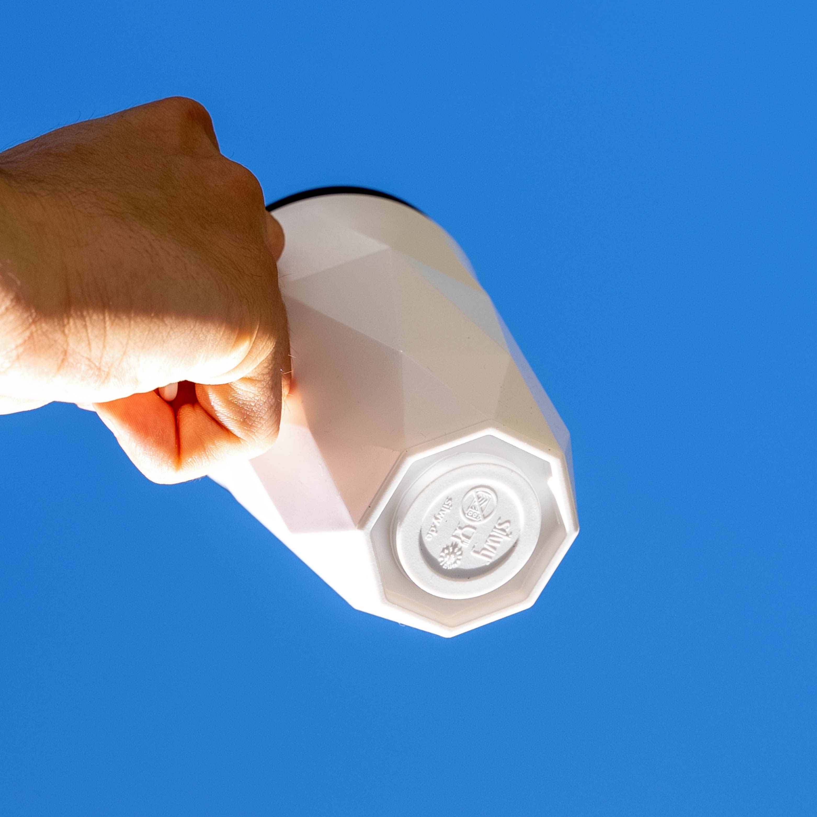 Magnet-Kunststofftasse TO-GO mit integriertem Magneten im Boden vor blauem Hintergrund 