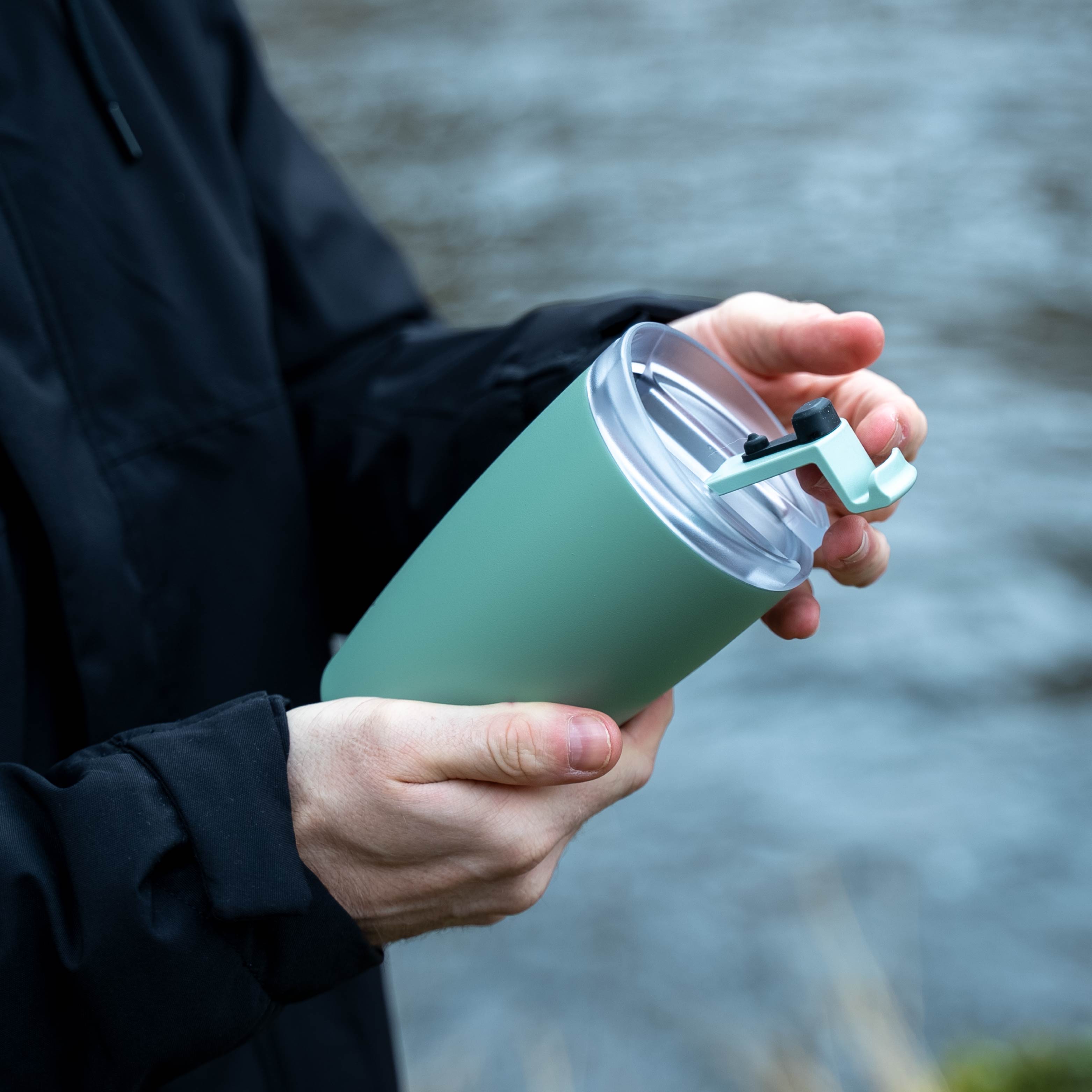 Der geöffnete silwy x FLSK Thermocup in der Farbe sage ist geöffnet und wird in der Hand gehalten