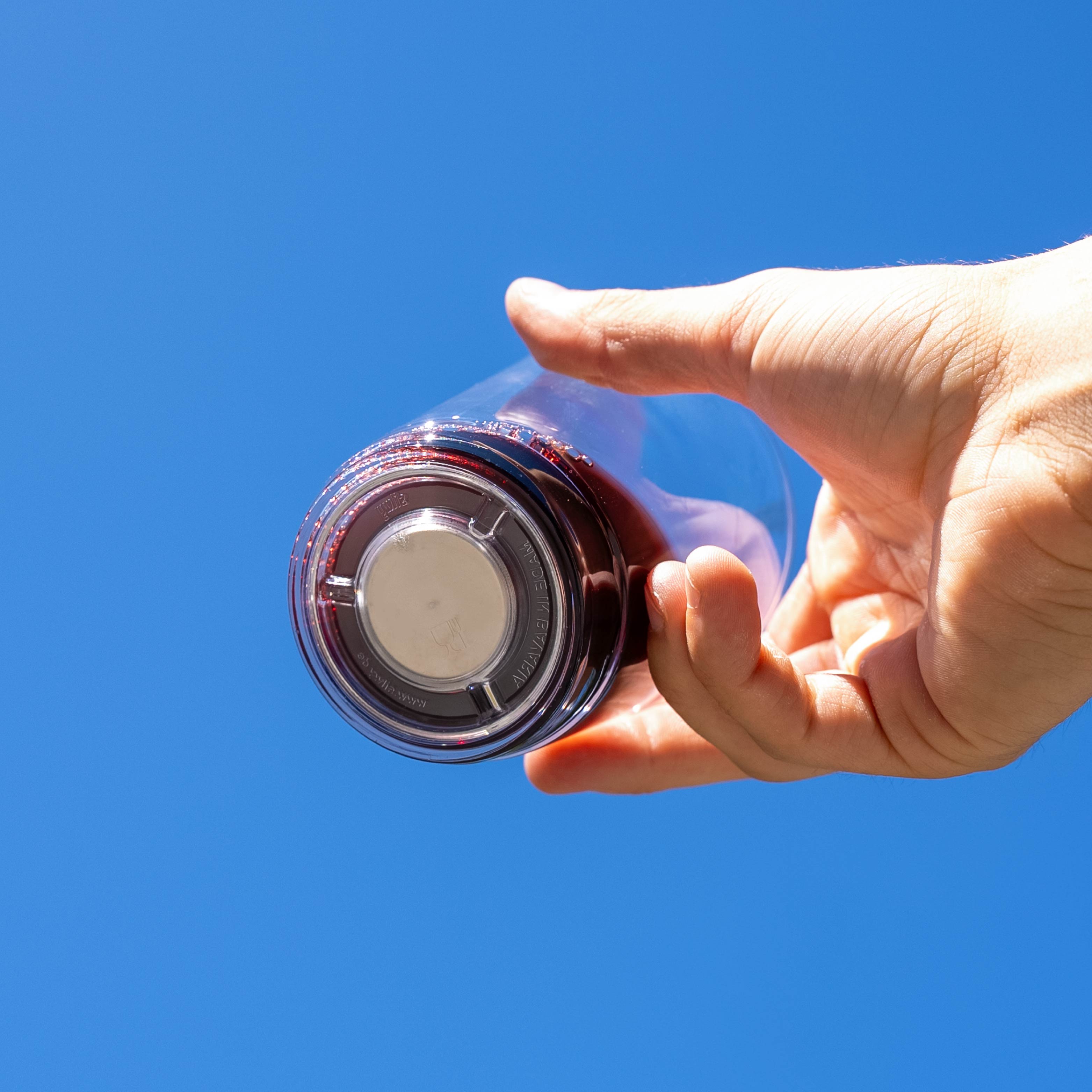 gefülltes Magnet-Glas mit integriertem Magneten im Boden vor blauem Hintergrund 