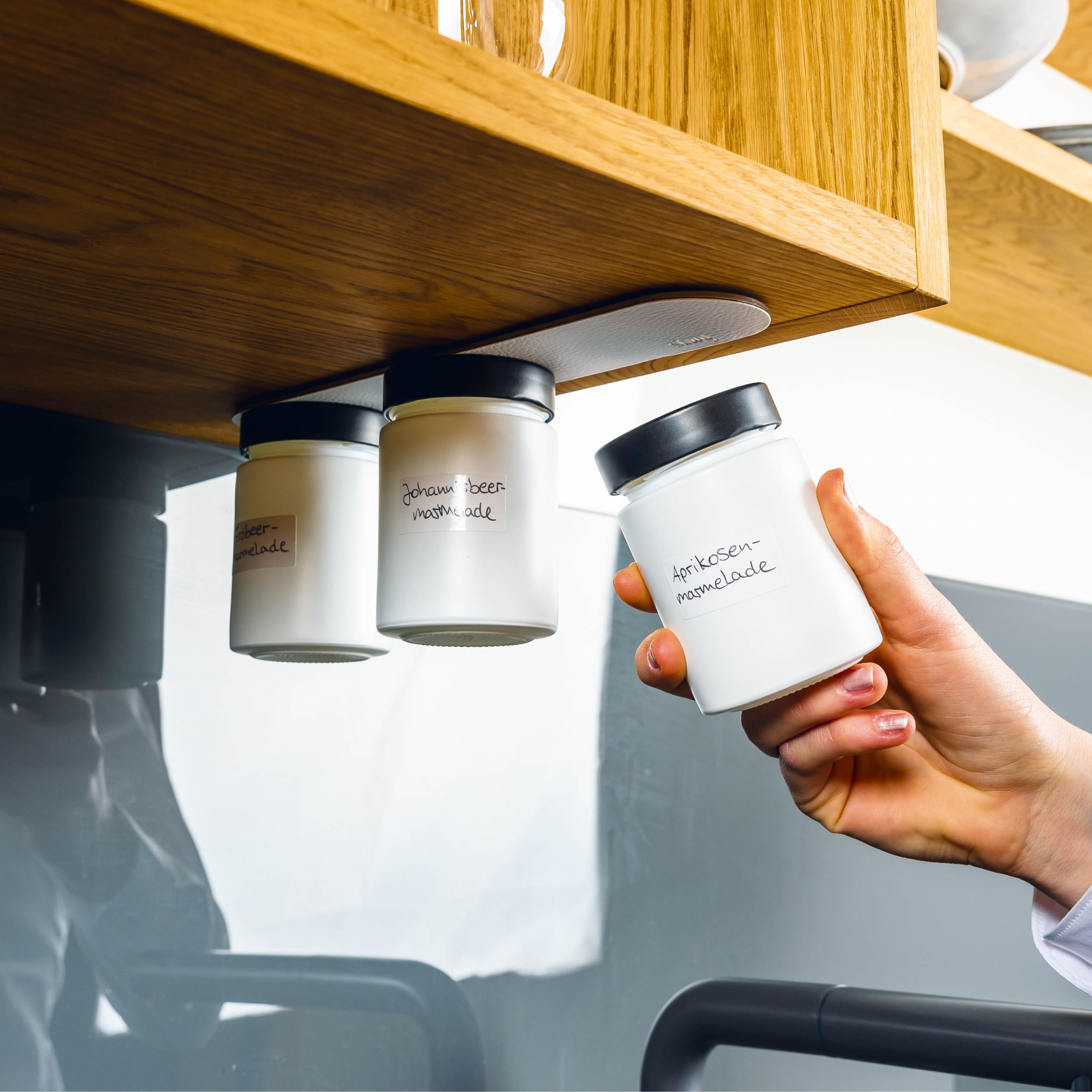 Magnet-Feinkostgläser an Metall-Leiste in Küchenumgebung montiert 