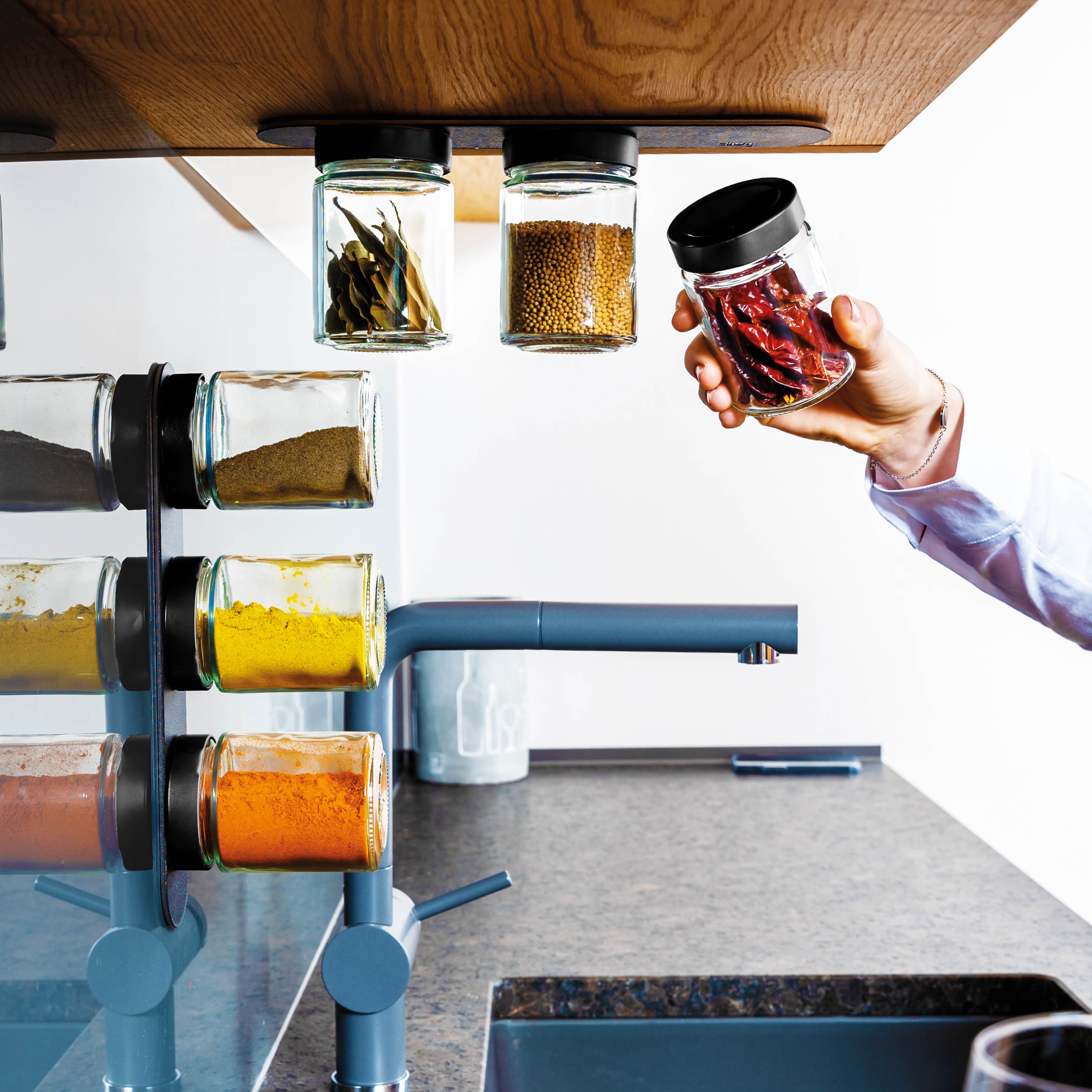 Magnet-Feinkostgläser an Metall-Leiste in Küchenumgebung montiert 