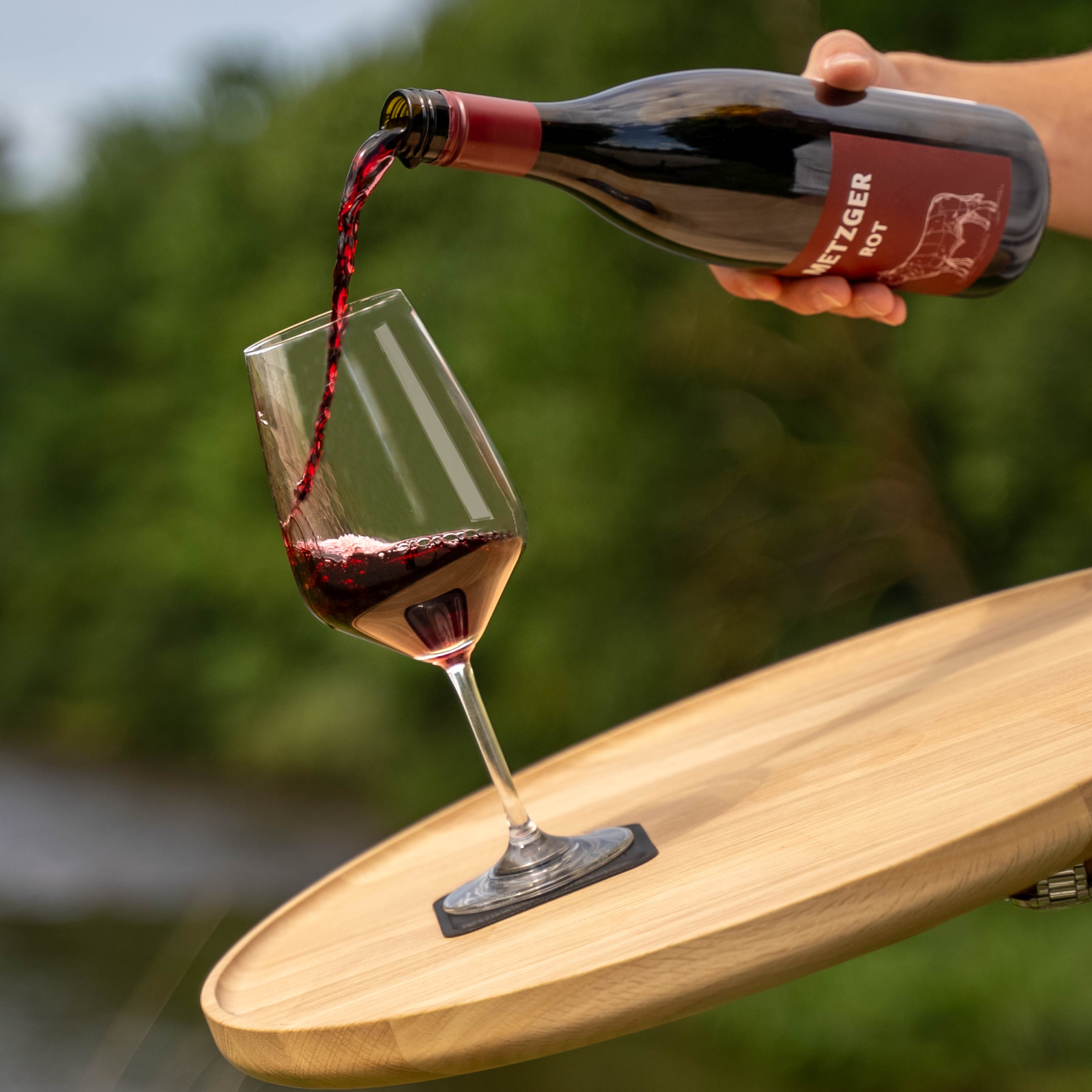 Magnet-Kristallglas Wein auf quadratischem Metall-Nano-Gel-Pad während Rotwein eingeschenkt wird 